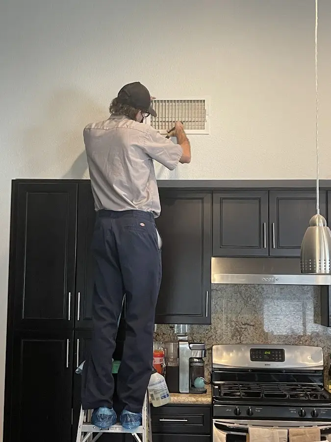 Technician inspecting an air vent during HVAC service in Dalton